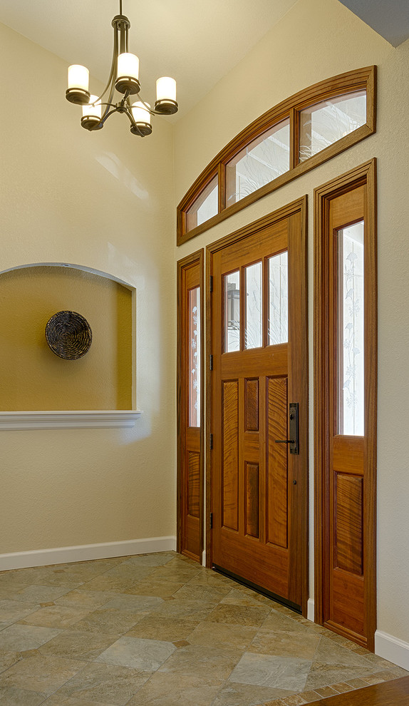 This is an example of an arts and crafts foyer in San Francisco with beige walls, porcelain floors, a single front door and a dark wood front door.