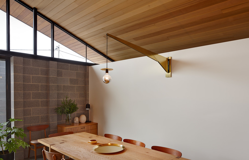 Photo of a contemporary kitchen/dining combo in Melbourne with white walls and concrete floors.