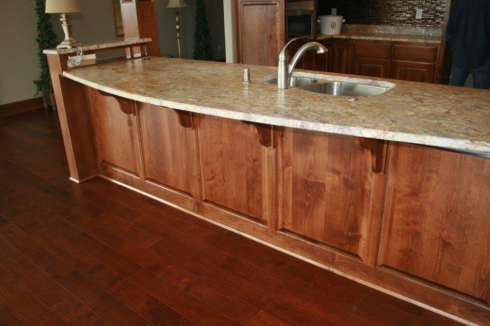 Example of a trendy dark wood floor and brown floor kitchen design with a double-bowl sink, medium tone wood cabinets, granite countertops, stainless steel appliances and an island
