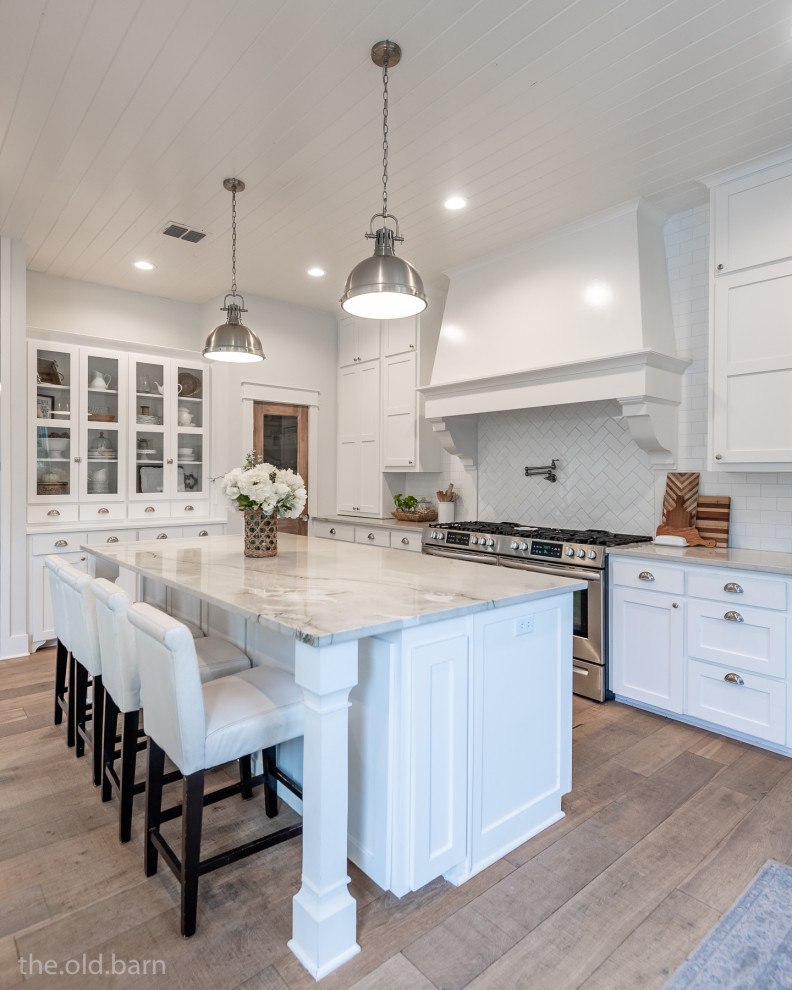 Country u-shaped open plan kitchen in Dallas with an undermount sink, shaker cabinets, white cabinets, quartzite benchtops, white splashback, subway tile splashback, stainless steel appliances, light hardwood floors, with island, brown floor, white benchtop and timber.
