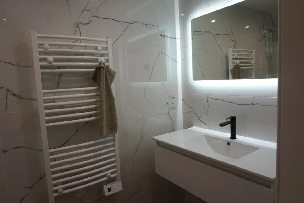 На фото: ванная комната среднего размера в стиле модернизм с белой плиткой, керамической плиткой, белыми стенами, полом из керамической плитки, душевой кабиной, консольной раковиной, коричневым полом и тумбой под одну раковину