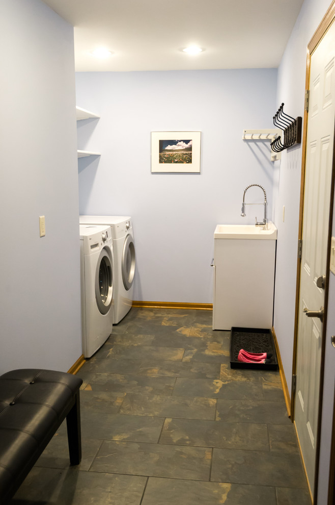 Dedicated laundry room - large transitional galley porcelain tile dedicated laundry room idea with an utility sink, open cabinets, white cabinets, solid surface countertops, blue walls and a side-by-side washer/dryer