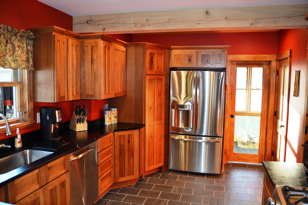 Inspiration for a mid-sized rustic l-shaped slate floor eat-in kitchen remodel in Burlington with an undermount sink, shaker cabinets, distressed cabinets, soapstone countertops, stainless steel appliances and a peninsula
