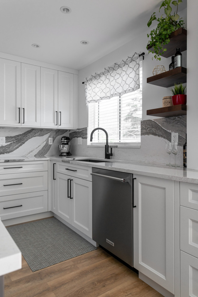 Inspiration for a mid-sized transitional u-shaped medium tone wood floor and brown floor eat-in kitchen remodel with an undermount sink, recessed-panel cabinets, white cabinets, quartz countertops, white backsplash, stone slab backsplash, stainless steel appliances, an island and white countertops