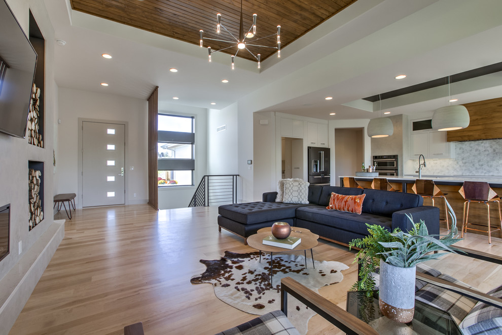Contemporary open concept living room in Omaha with white walls, light hardwood floors, a ribbon fireplace, a concrete fireplace surround and a wall-mounted tv.