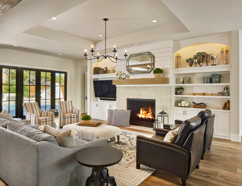Inspiration for a country open concept living room in Dallas with white walls, medium hardwood floors, a standard fireplace, a stone fireplace surround, a wall-mounted tv, brown floor and planked wall panelling.