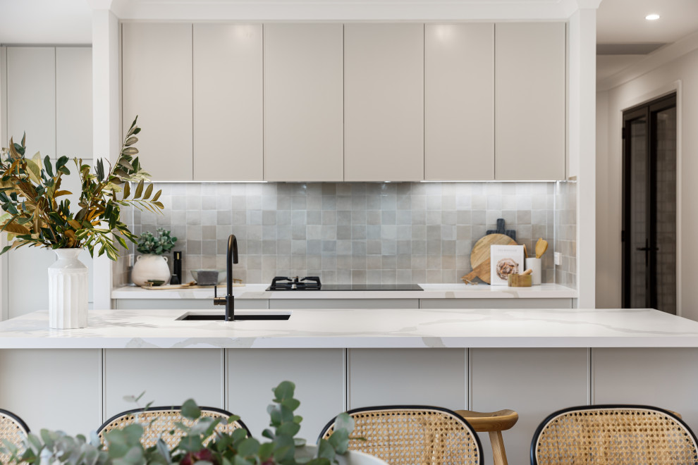 Inspiration for a mid-sized contemporary single-wall open plan kitchen in Wollongong with an undermount sink, grey cabinets, solid surface benchtops, grey splashback, porcelain splashback, black appliances, light hardwood floors, with island and white benchtop.