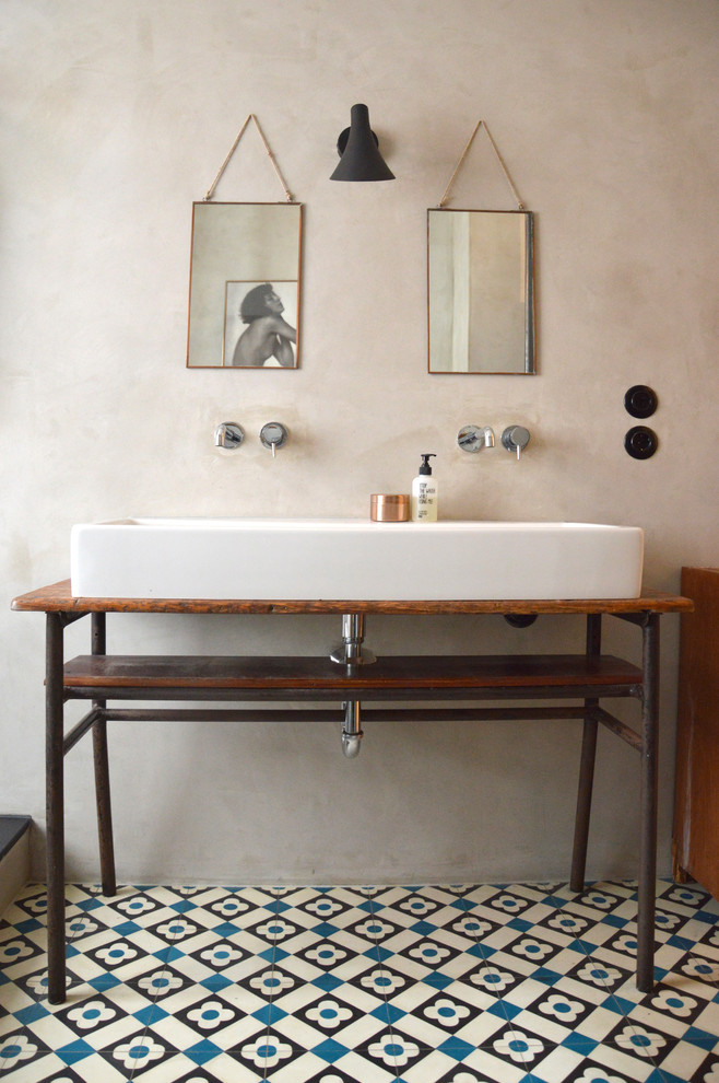 Photo of an industrial bathroom in Berlin with blue tile, black tile, white tile, cement tile, wood benchtops, grey walls, ceramic floors and a trough sink.