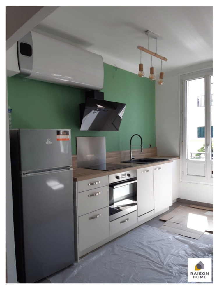 This is an example of a small modern single-wall open plan kitchen in Paris with an undermount sink, flat-panel cabinets, white cabinets, wood benchtops, brown splashback, timber splashback, panelled appliances, cement tiles, with island, grey floor, brown benchtop and wallpaper.