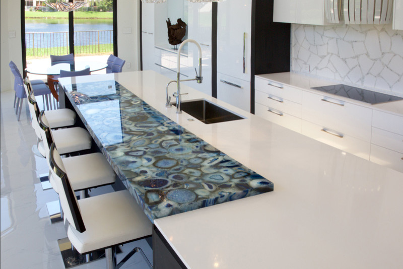 Photo of an expansive contemporary galley open plan kitchen in Paris with an undermount sink, open cabinets, white cabinets, quartzite benchtops, white splashback, glass tile splashback, white appliances and with island.