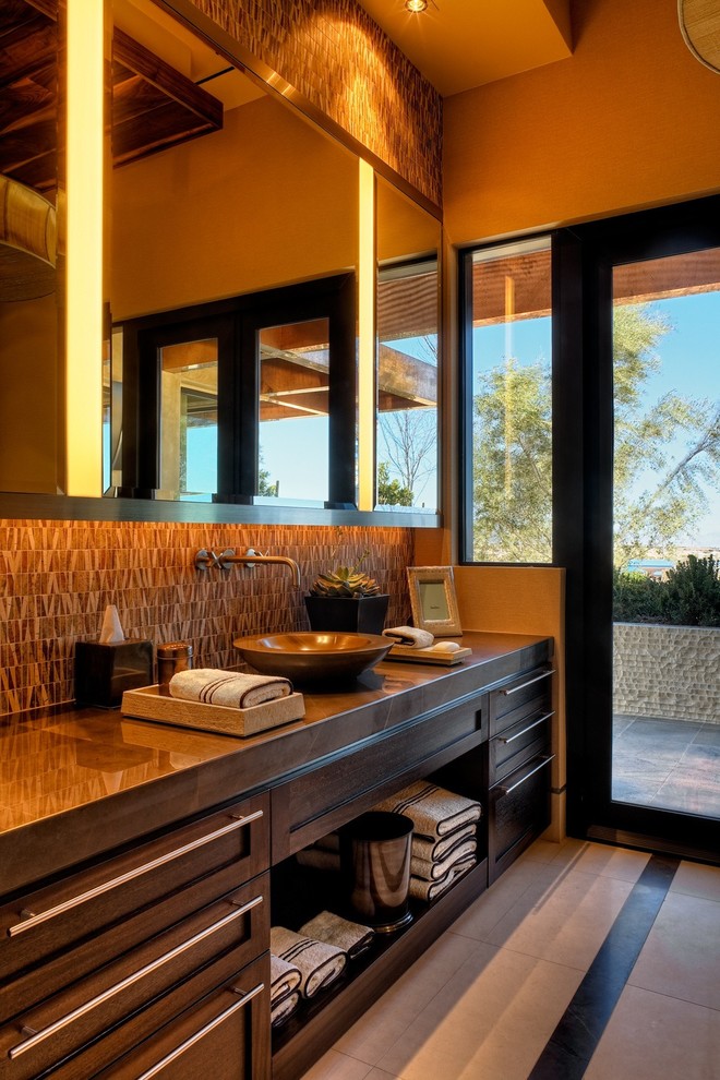 Trendy brown tile bathroom photo in Las Vegas with a vessel sink, recessed-panel cabinets and dark wood cabinets