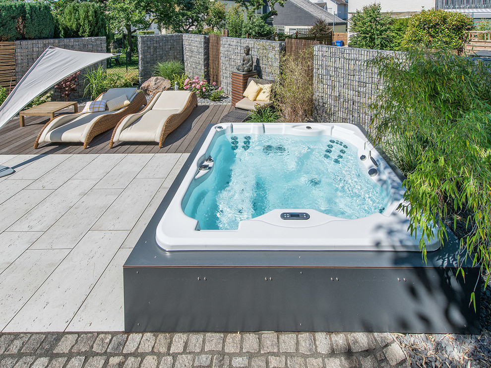 Design ideas for a small contemporary backyard custom-shaped aboveground pool in Frankfurt with a hot tub.