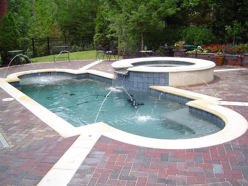 Example of a mid-sized trendy backyard brick and custom-shaped natural hot tub design