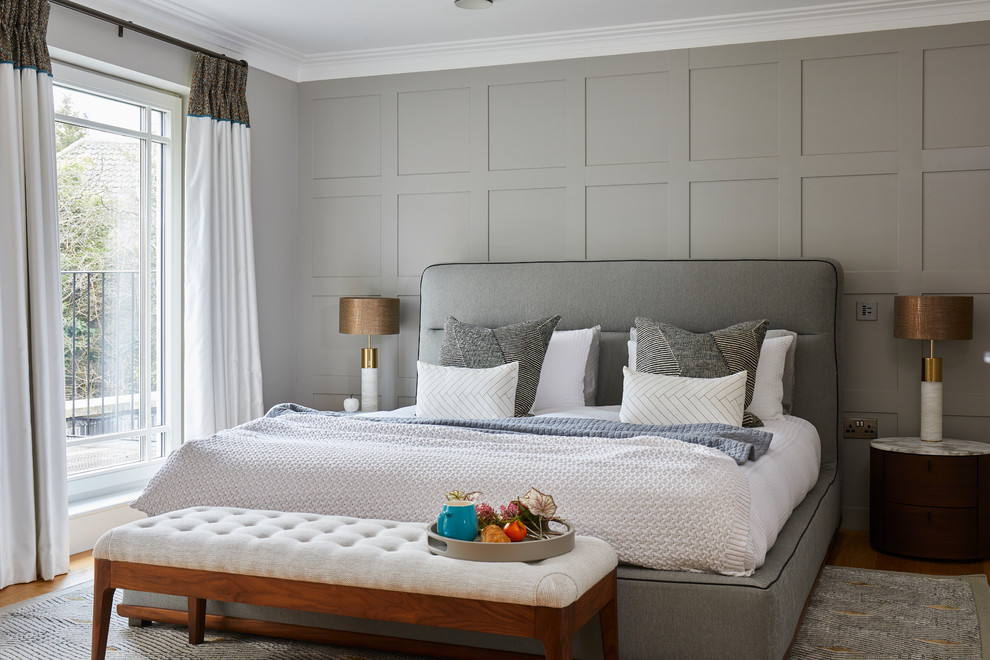 Large contemporary bedroom in Surrey with grey walls, medium hardwood floors and brown floor.