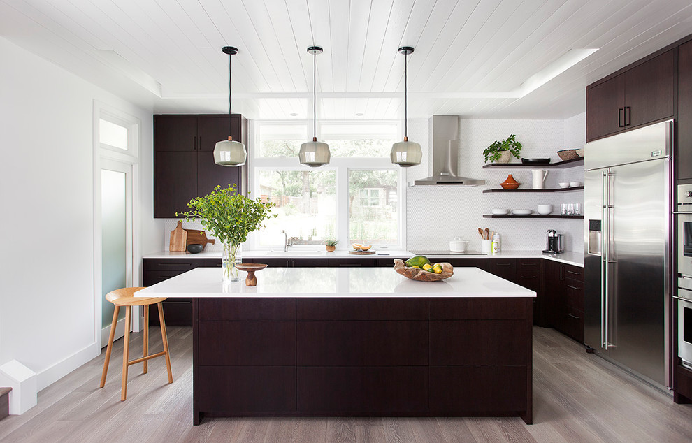 Design ideas for a modern u-shaped eat-in kitchen in Austin with a drop-in sink, flat-panel cabinets, dark wood cabinets, quartzite benchtops, white splashback, mosaic tile splashback, stainless steel appliances, light hardwood floors and with island.