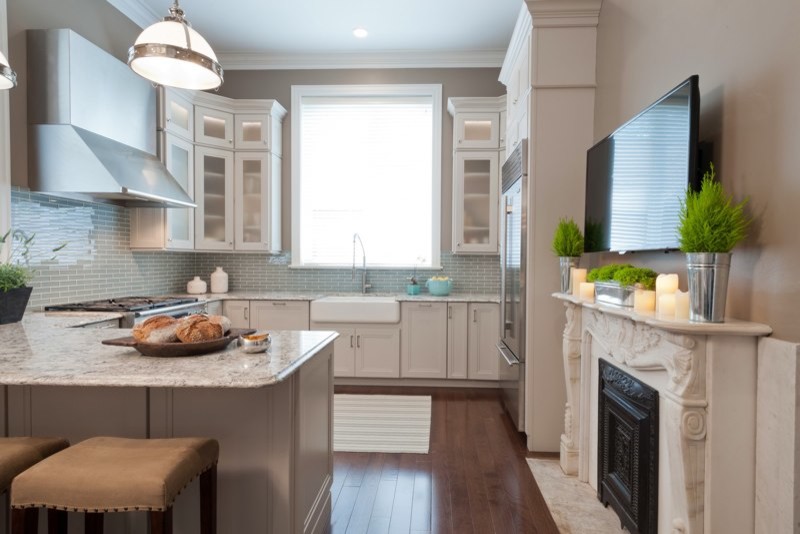 Design ideas for a mid-sized transitional l-shaped eat-in kitchen in St Louis with a farmhouse sink, quartz benchtops, blue splashback, glass tile splashback, stainless steel appliances, dark hardwood floors, recessed-panel cabinets, white cabinets and a peninsula.