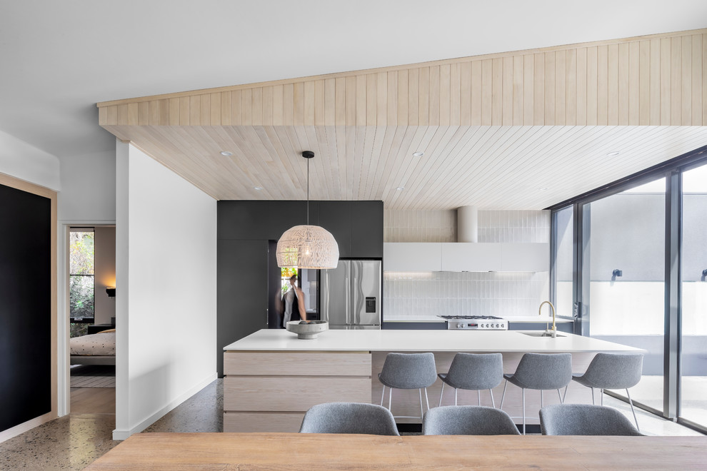 Contemporary galley eat-in kitchen in Adelaide with an undermount sink, flat-panel cabinets, light wood cabinets, white splashback, stainless steel appliances, concrete floors, with island, grey floor and white benchtop.