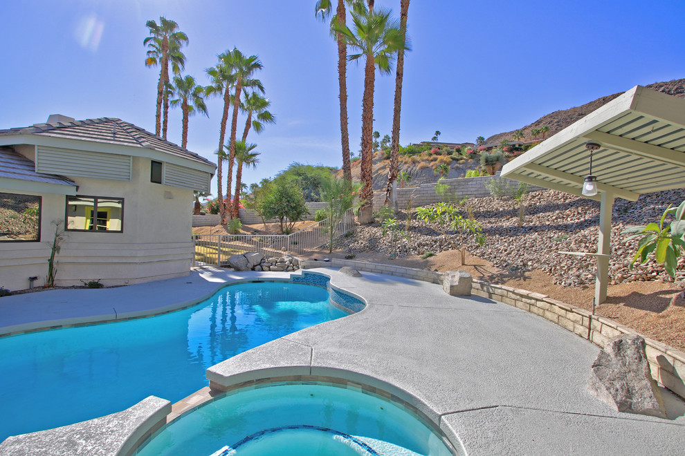 Example of a mid-sized transitional backyard concrete and custom-shaped natural hot tub design