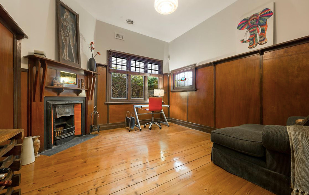 Small traditional enclosed living room in Melbourne with a library, beige walls, medium hardwood floors, a standard fireplace, a wood fireplace surround and no tv.