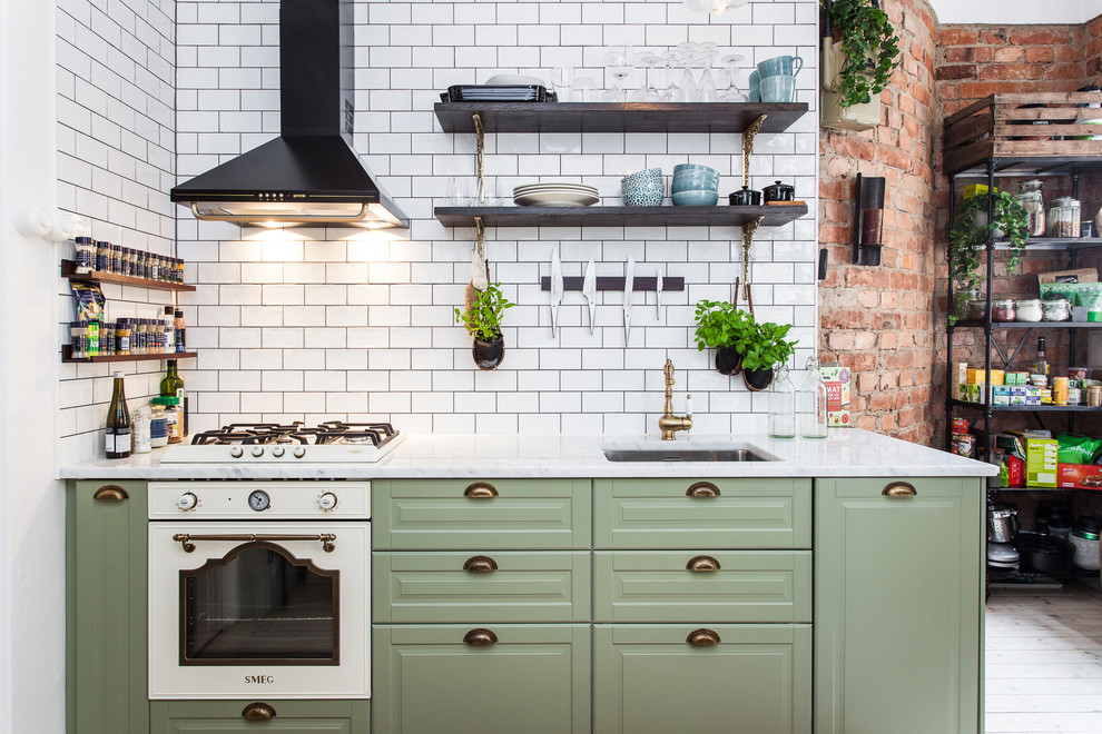 Inspiration for a large scandinavian l-shaped eat-in kitchen in Stockholm with an undermount sink, raised-panel cabinets, green cabinets, white splashback, subway tile splashback, light hardwood floors and no island.