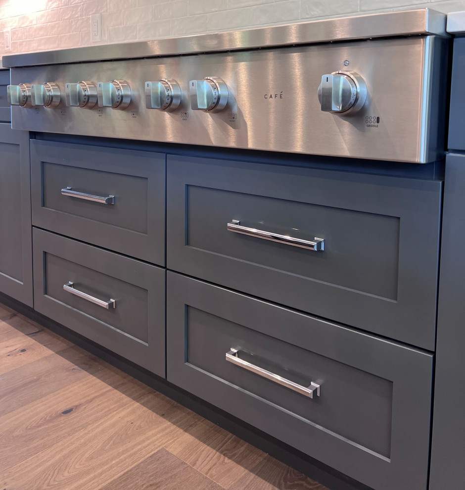 Large transitional kitchen photo with an undermount sink, shaker cabinets, gray cabinets, quartz countertops, white backsplash, stainless steel appliances, two islands and white countertops