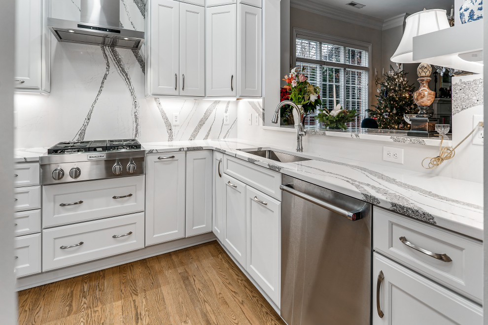 Enclosed kitchen - mid-sized transitional u-shaped medium tone wood floor enclosed kitchen idea in Charlotte with an undermount sink, shaker cabinets, white cabinets, quartz countertops, quartz backsplash, stainless steel appliances and no island