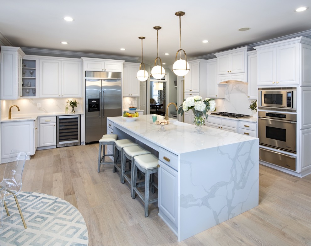 Transitional l-shaped beige floor eat-in kitchen photo with stainless steel appliances, shaker cabinets, white cabinets, white backsplash, an island and white countertops