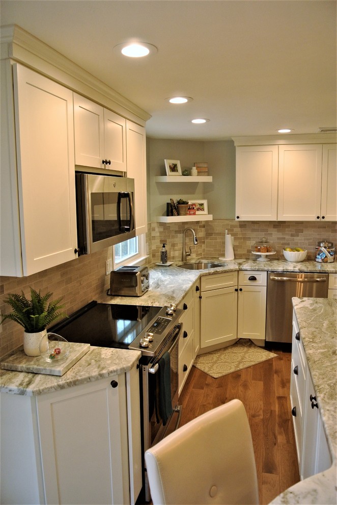 Example of a transitional l-shaped medium tone wood floor kitchen design in Boston with an undermount sink, shaker cabinets, white cabinets, granite countertops, beige backsplash, subway tile backsplash, stainless steel appliances and an island