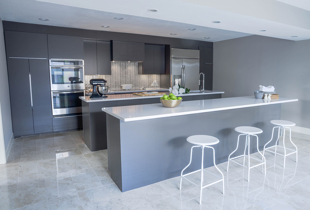 Large contemporary single-wall kitchen in Houston with an undermount sink, flat-panel cabinets, grey cabinets, quartz benchtops, grey splashback, glass tile splashback, stainless steel appliances, ceramic floors and multiple islands.