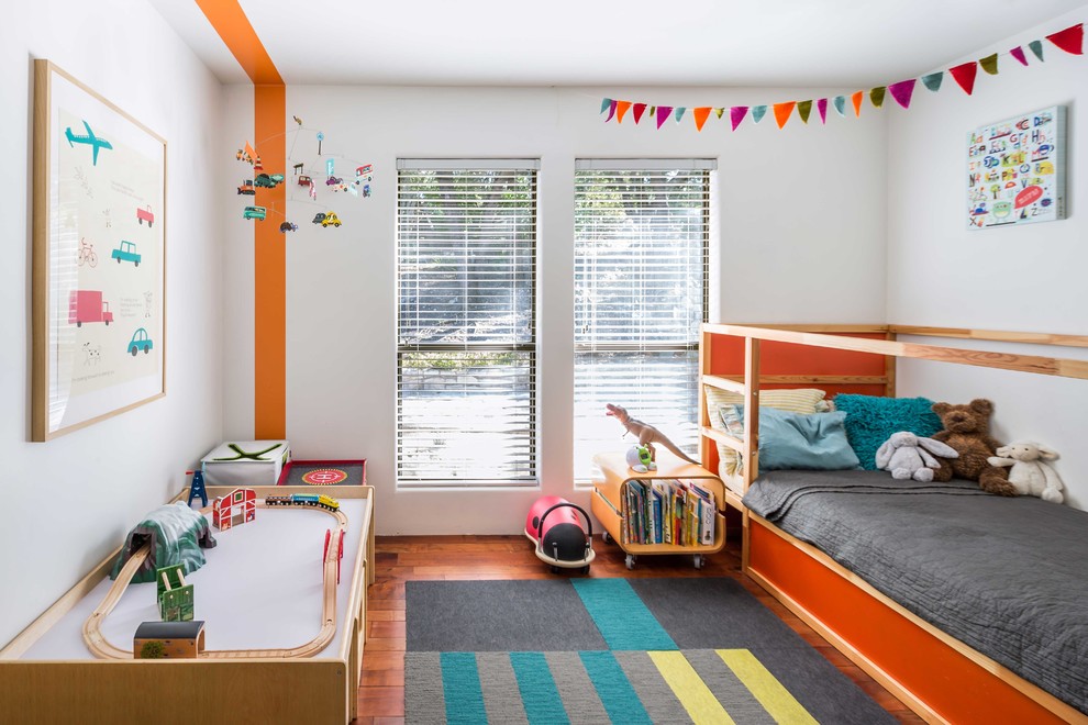 Midcentury gender-neutral kids' room in Austin with multi-coloured walls and medium hardwood floors.