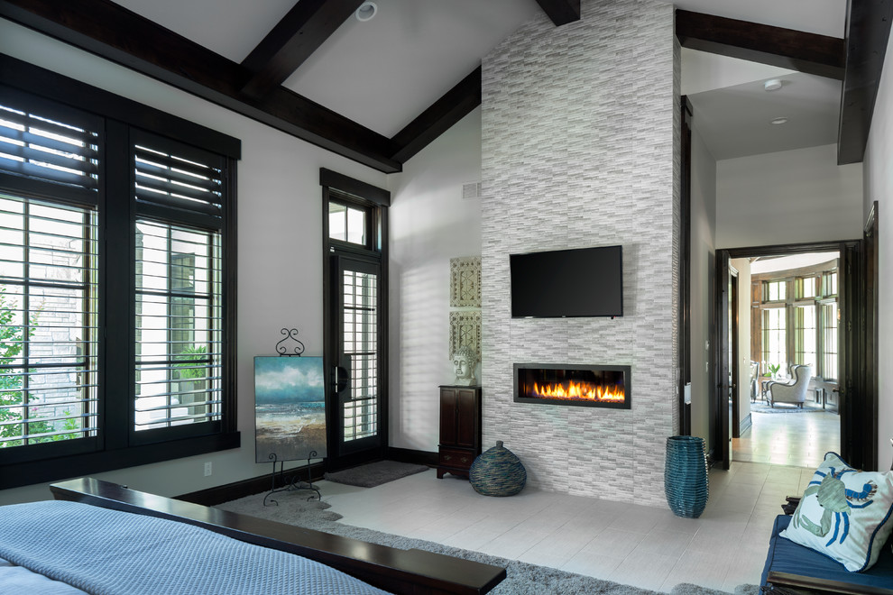 Photo of a large contemporary master bedroom in Kansas City with grey walls, a two-sided fireplace, a stone fireplace surround and porcelain floors.