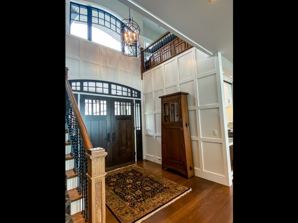 Inspiration for a transitional wall paneling foyer remodel with white walls and a dark wood front door