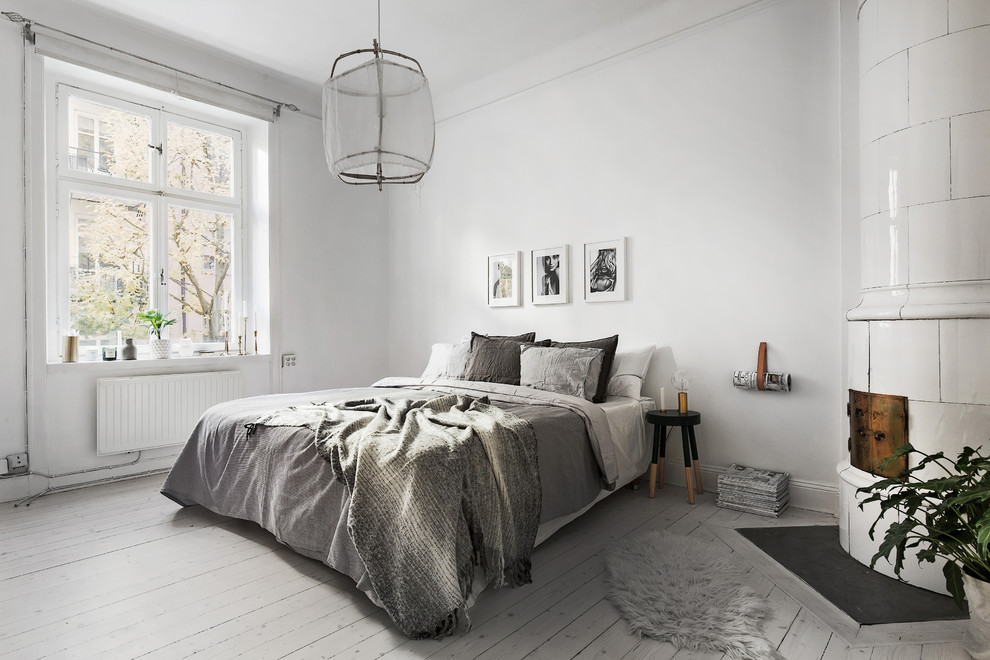 Large scandinavian master bedroom in Stockholm with white walls, painted wood floors and no fireplace.