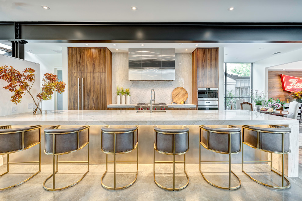 Contemporary galley open plan kitchen in Houston with a single-bowl sink, flat-panel cabinets, medium wood cabinets, quartzite benchtops, beige splashback, stone slab splashback, panelled appliances, concrete floors, with island, grey floor, beige benchtop and exposed beam.