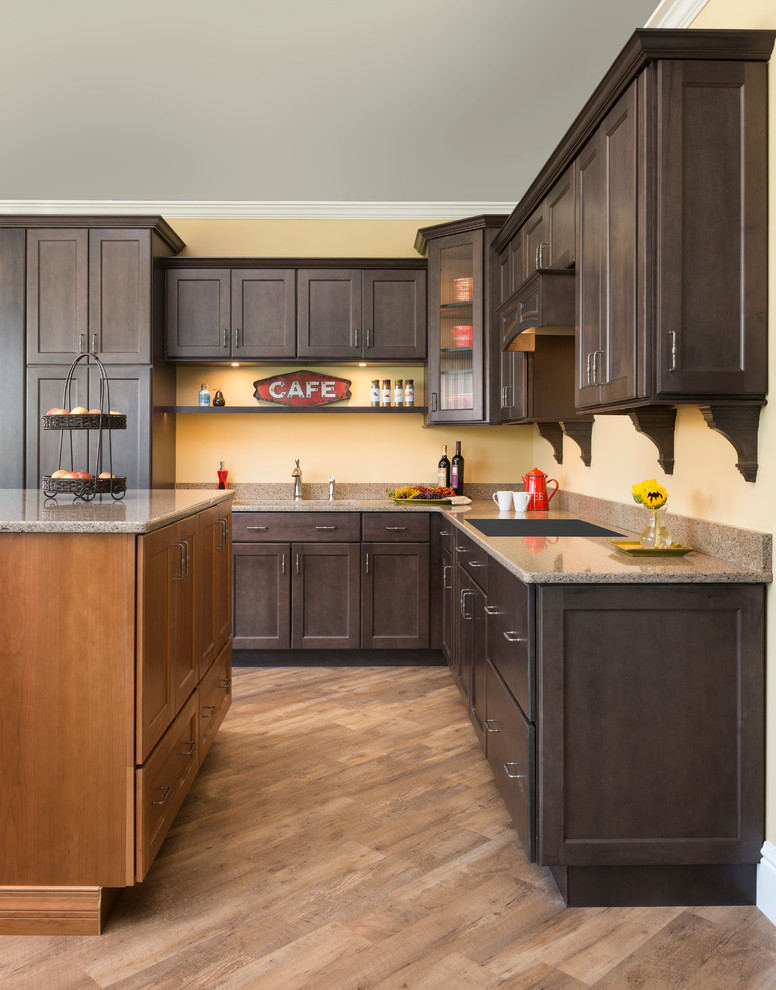 Photo of a mid-sized traditional l-shaped eat-in kitchen in Providence with an undermount sink, recessed-panel cabinets, dark wood cabinets, granite benchtops, yellow splashback, light hardwood floors and with island.