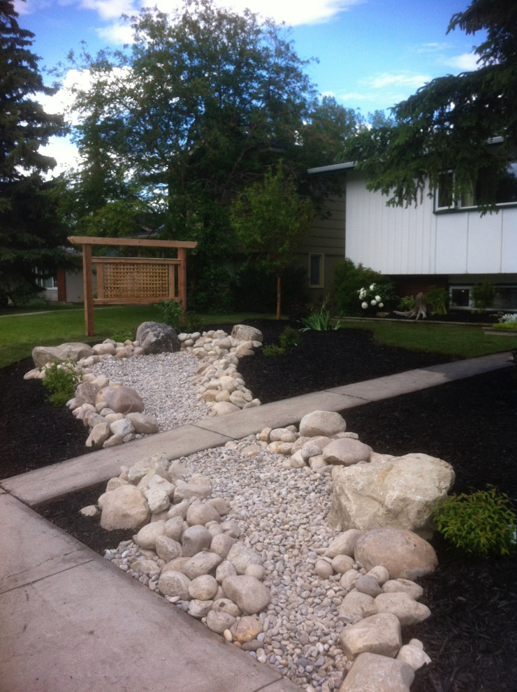 This is an example of a small traditional front yard xeriscape in Calgary with with rock feature and river rock.