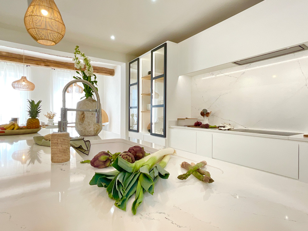 Inspiration for a large mediterranean galley open plan kitchen in Marseille with an undermount sink, flat-panel cabinets, white cabinets, white splashback, marble splashback, panelled appliances, travertine floors, with island, beige floor and white benchtop.