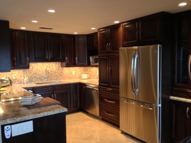 Large transitional u-shaped ceramic tile eat-in kitchen photo in Miami with an undermount sink, raised-panel cabinets, dark wood cabinets, granite countertops, beige backsplash, stone tile backsplash, stainless steel appliances and an island