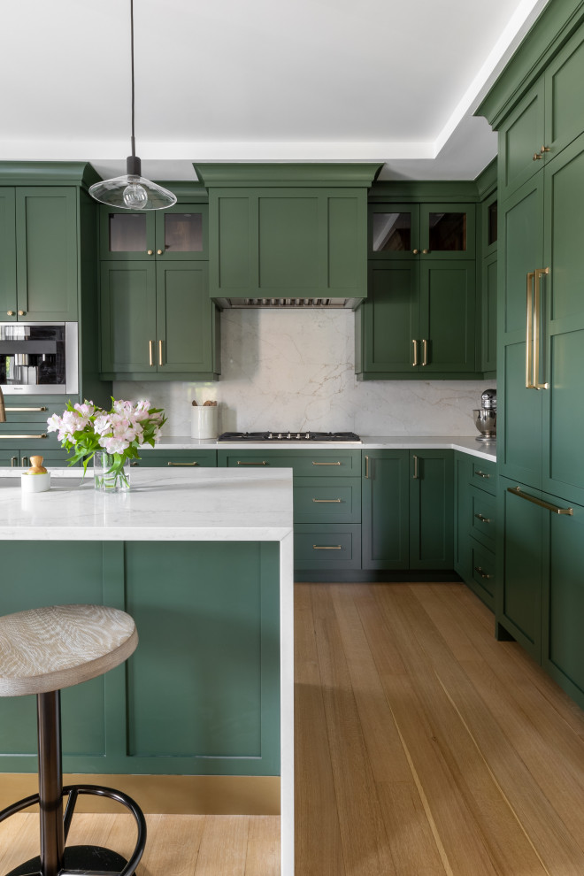 Inspiration for a large transitional l-shaped eat-in kitchen in Detroit with an undermount sink, shaker cabinets, green cabinets, quartz benchtops, white splashback, engineered quartz splashback, stainless steel appliances, light hardwood floors, with island, brown floor, white benchtop and recessed.