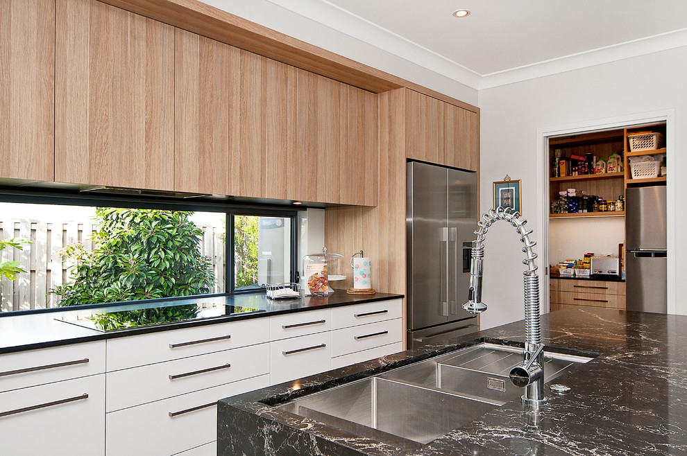 Photo of a mid-sized modern l-shaped open plan kitchen in Gold Coast - Tweed with an undermount sink, flat-panel cabinets, light wood cabinets, quartz benchtops, glass sheet splashback, stainless steel appliances, ceramic floors and with island.