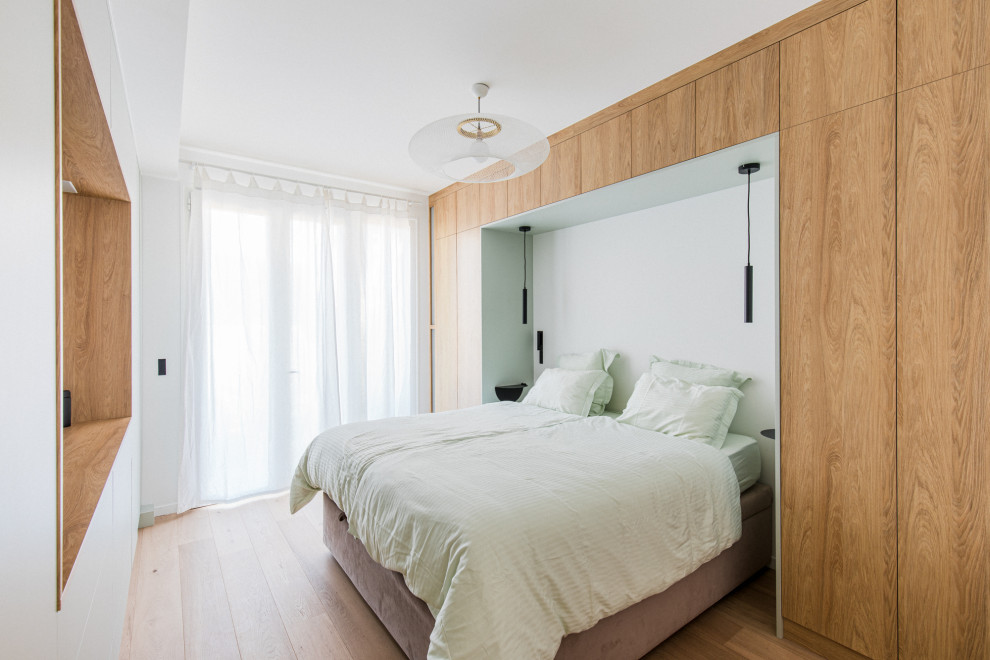 Mittelgroßes Nordisches Hauptschlafzimmer ohne Kamin mit weißer Wandfarbe und hellem Holzboden in Paris