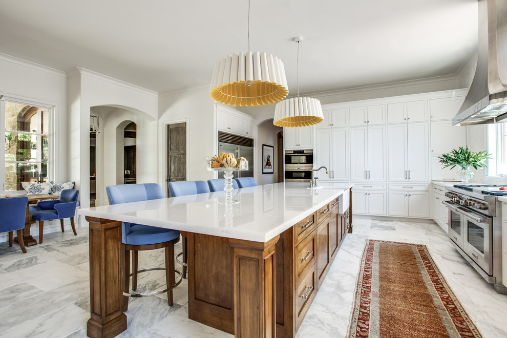 Expansive transitional single-wall open plan kitchen in Dallas with a farmhouse sink, shaker cabinets, white cabinets, marble benchtops, white splashback, mosaic tile splashback, stainless steel appliances, marble floors and with island.