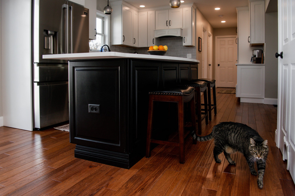 Foto på ett stort vintage vit kök, med en undermonterad diskho, luckor med upphöjd panel, svarta skåp, bänkskiva i kvarts, stänkskydd med metallisk yta, rostfria vitvaror, mellanmörkt trägolv, en köksö och orange golv