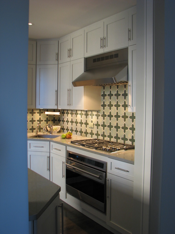 Example of a mid-sized transitional l-shaped eat-in kitchen design in New York with an undermount sink, shaker cabinets, white cabinets, quartz countertops, multicolored backsplash, cement tile backsplash, stainless steel appliances and a peninsula