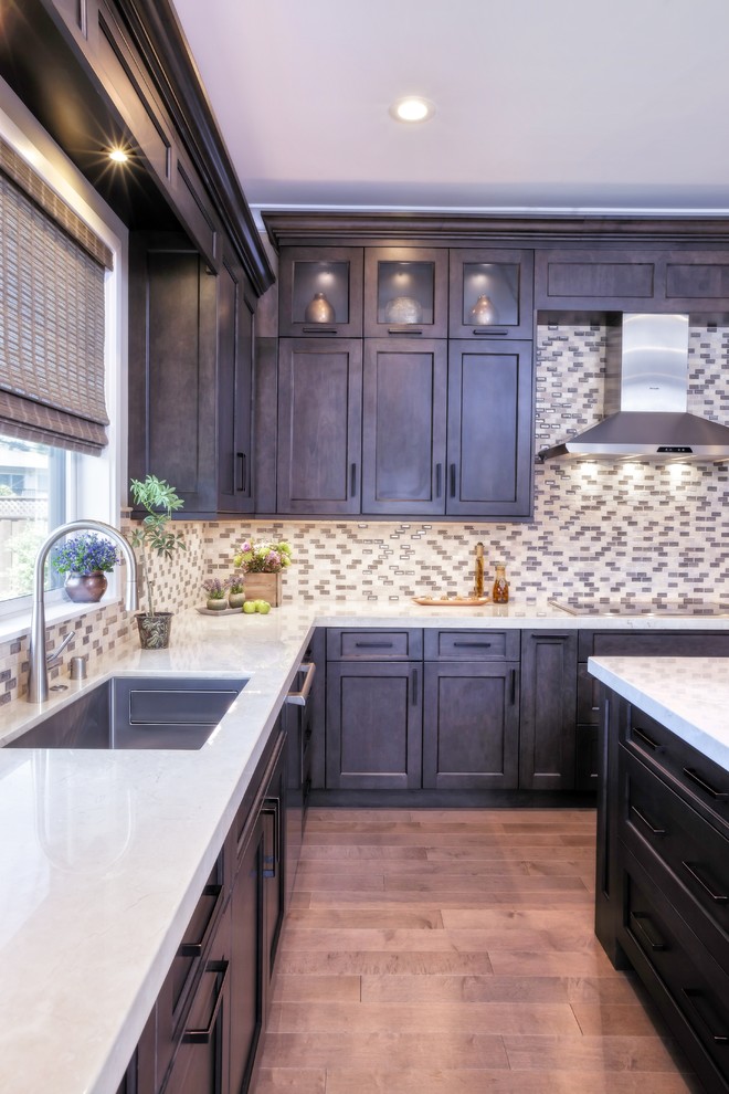 Example of a large transitional u-shaped medium tone wood floor and brown floor eat-in kitchen design with an undermount sink, recessed-panel cabinets, brown cabinets, marble countertops, multicolored backsplash, porcelain backsplash, stainless steel appliances and an island