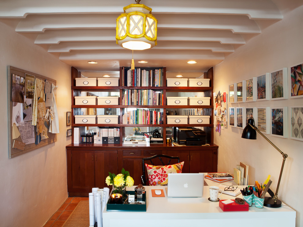 This is an example of a small transitional home office in San Francisco with a freestanding desk, white walls, terra-cotta floors and no fireplace.