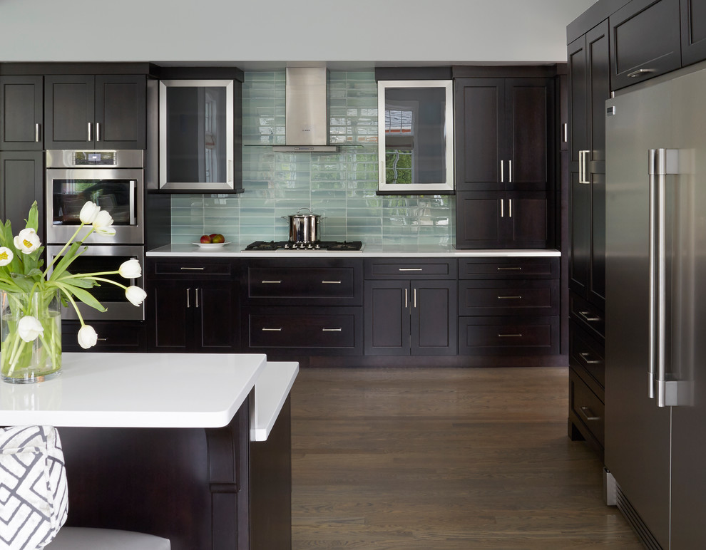 Inspiration for a large transitional l-shaped eat-in kitchen in Chicago with an undermount sink, shaker cabinets, dark wood cabinets, quartz benchtops, blue splashback, ceramic splashback, stainless steel appliances, light hardwood floors and with island.