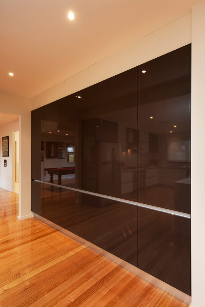 This is an example of a large modern galley kitchen in Melbourne with flat-panel cabinets and medium hardwood floors.