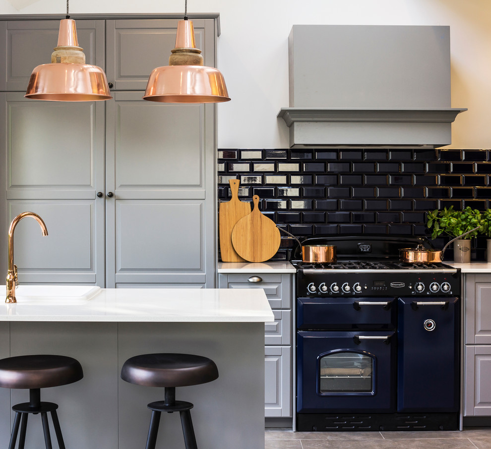 Inspiration for a large country open plan kitchen in London with raised-panel cabinets, grey cabinets, solid surface benchtops, blue splashback, ceramic splashback, coloured appliances, porcelain floors and with island.