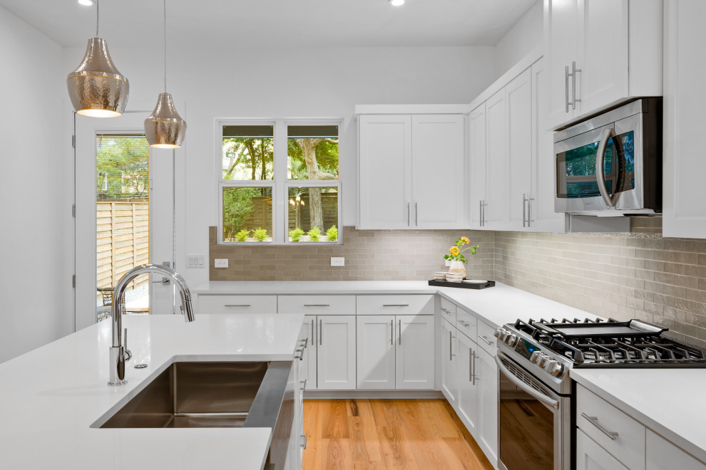 Inspiration for a mid-sized contemporary l-shaped light wood floor kitchen remodel in Austin with a farmhouse sink, shaker cabinets, quartz countertops, stainless steel appliances and an island